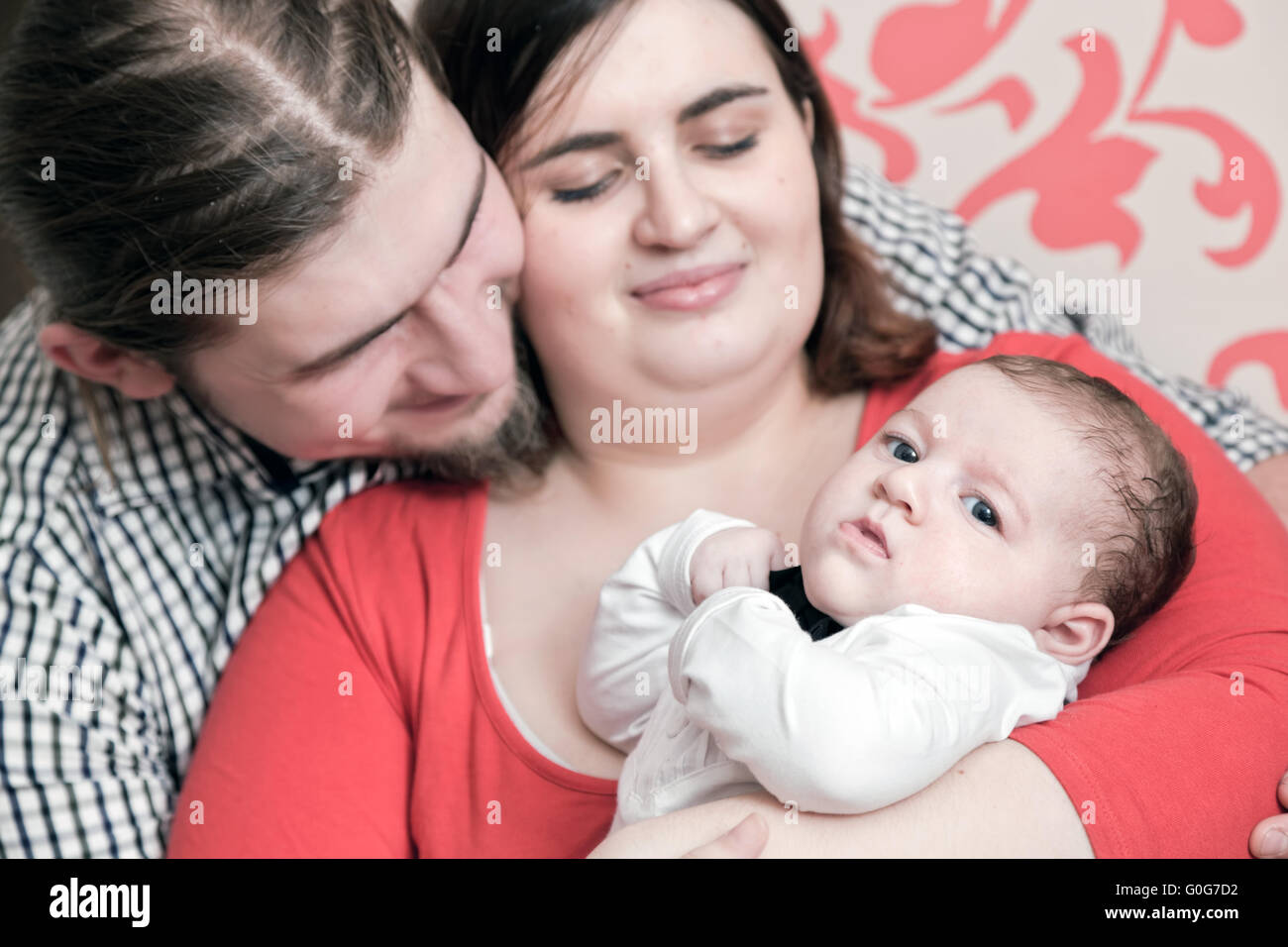 Mère et père avec leur jeune bébé câlins ensemble. Happy Family portrait. Banque D'Images