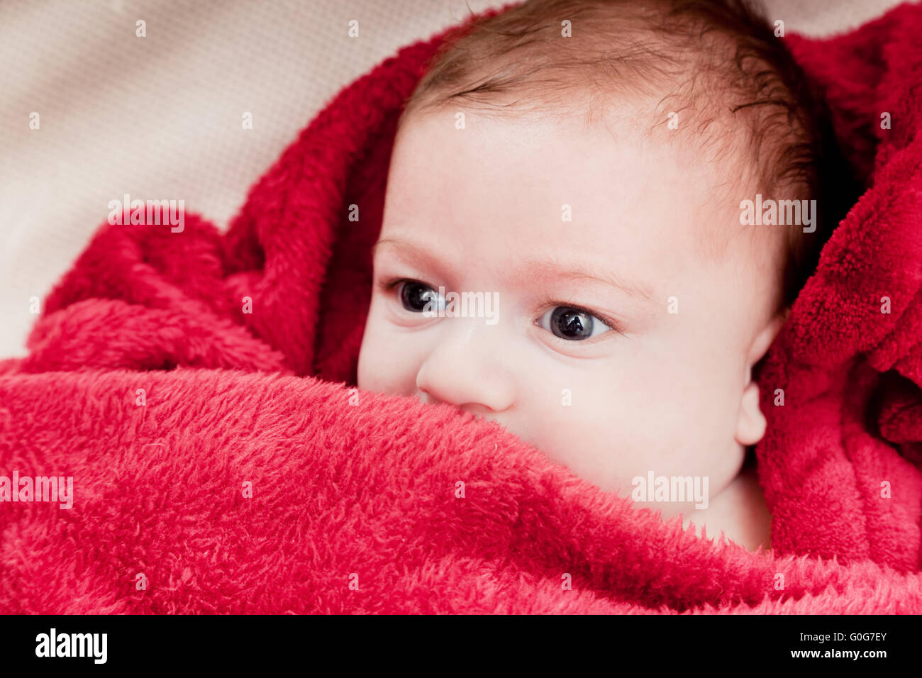 Beau 3 mois bébé couché sur un lit recouvert d'une couverture rouge. Portrait doux Banque D'Images