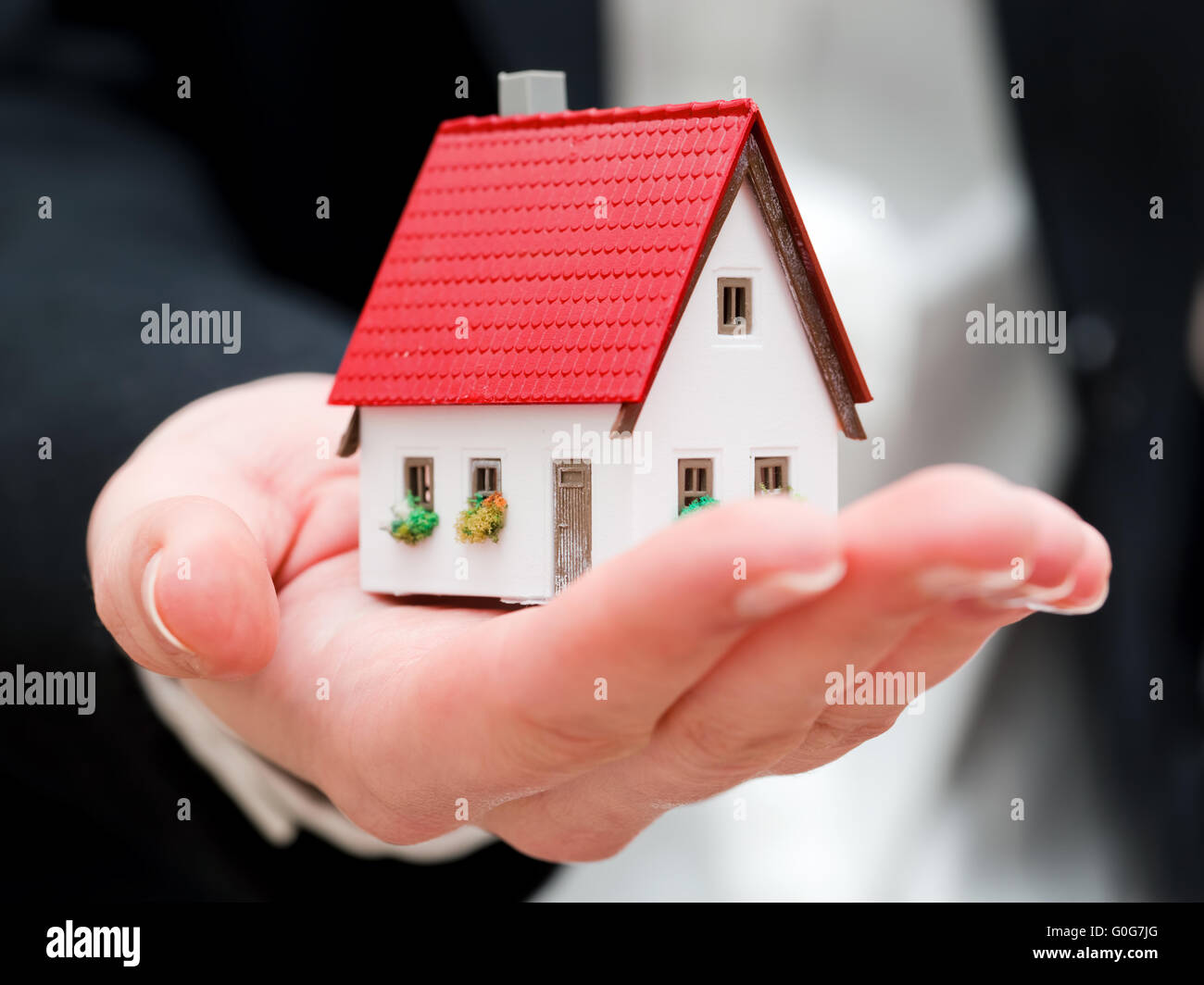 Un agent immobilier tenant une petite nouvelle maison dans ses mains. Conceptual Banque D'Images