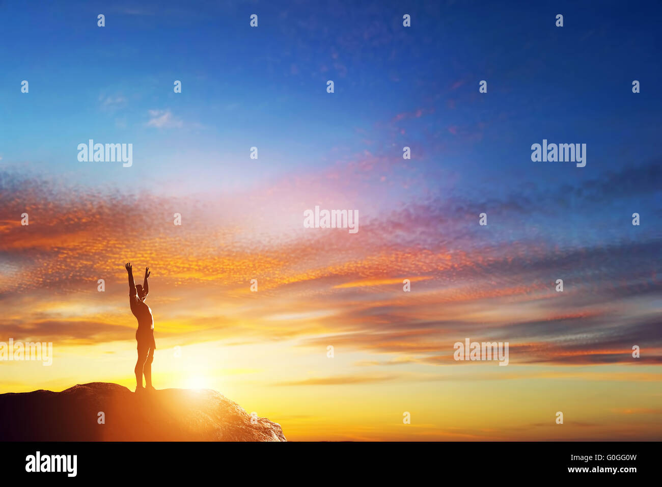 Happy man with hands up debout sur le sommet de la montagne au coucher du soleil magnifique. Profiter de la vie ! Banque D'Images