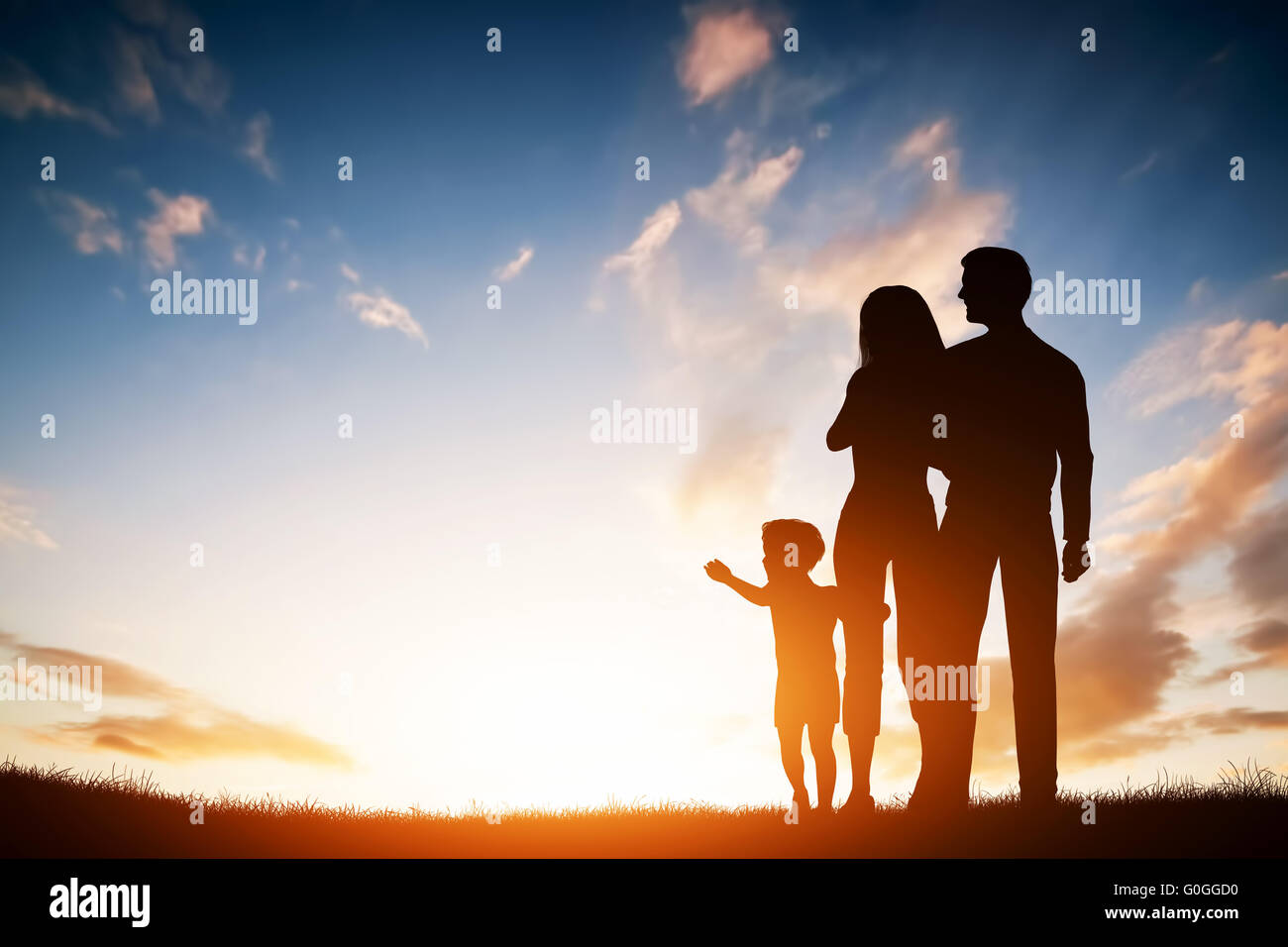 Famille heureuse ensemble, les parents avec leur petit enfant au coucher du soleil. Banque D'Images