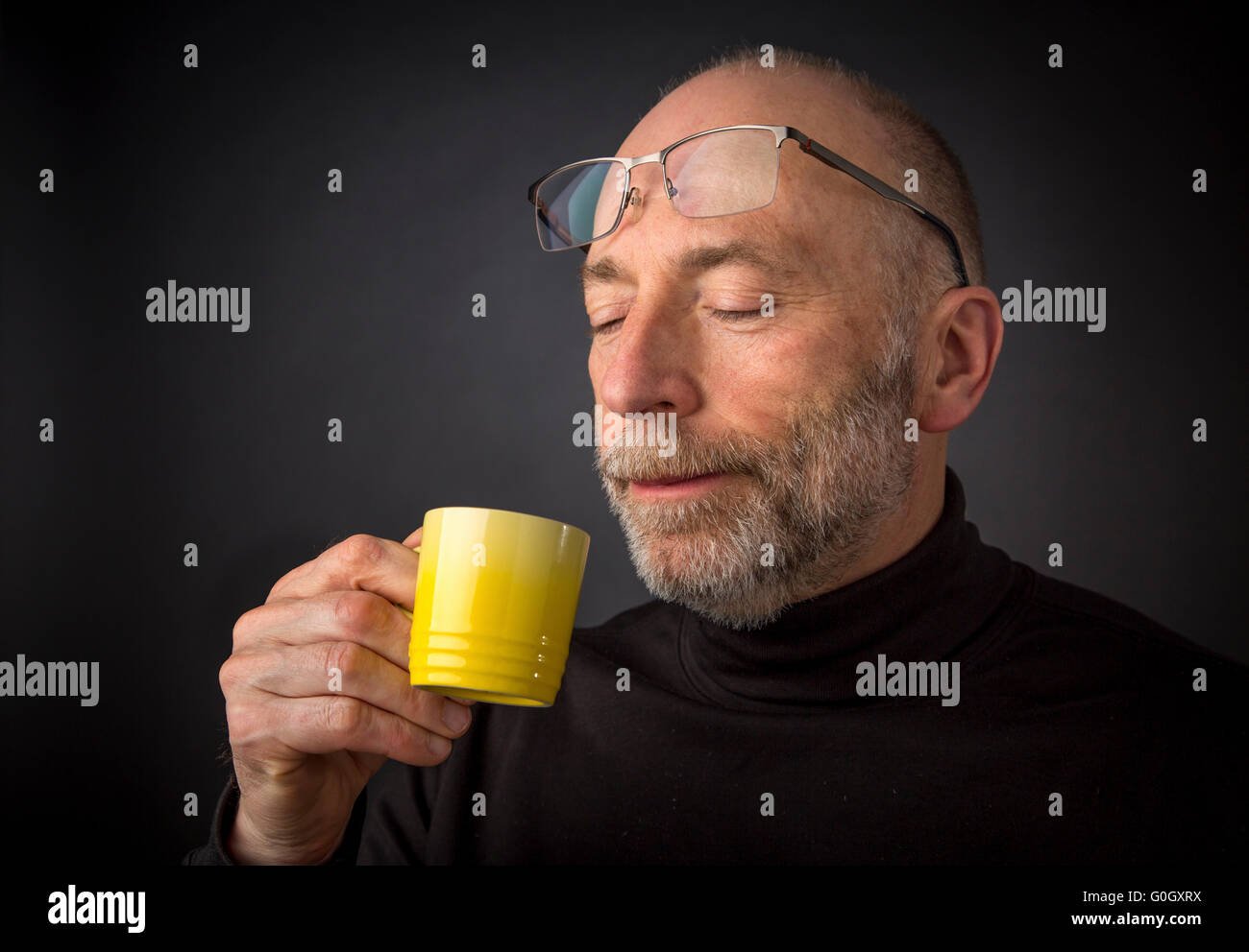 Bénéficiant d matin café espresso - 60 ans homme avec une barbe et des lunettes - un très gros plan sur un fond noir Banque D'Images