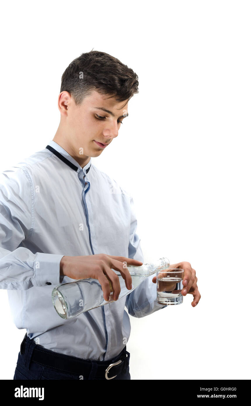 Homme garçon adolescent verser de l'eau de la bouteille en verre dans un verre isolé sur fond blanc Banque D'Images