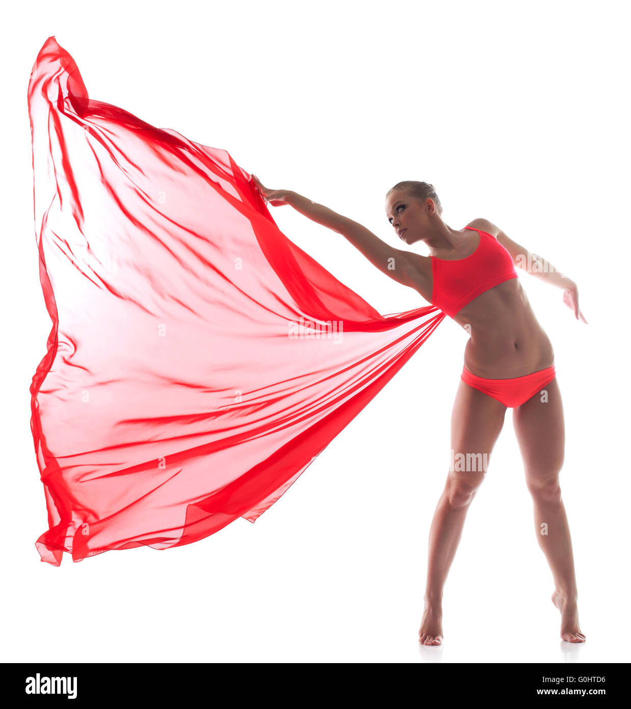 Danseuse souple posant avec tissu rouge dans le studio Banque D'Images