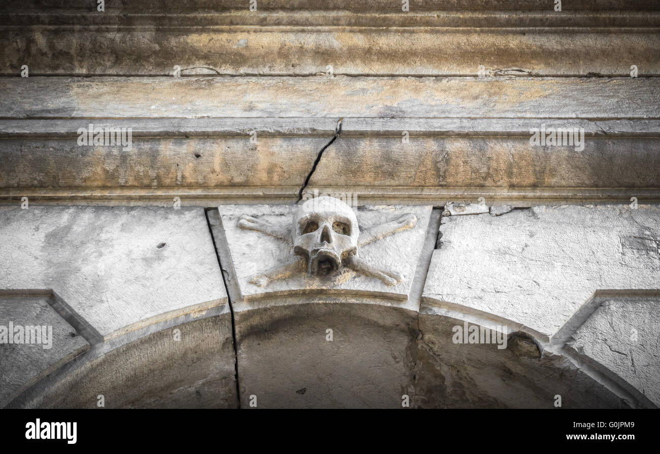 Un crâne de pierre placé près de l'entrée d'un charnier, dans un cimetière. Banque D'Images