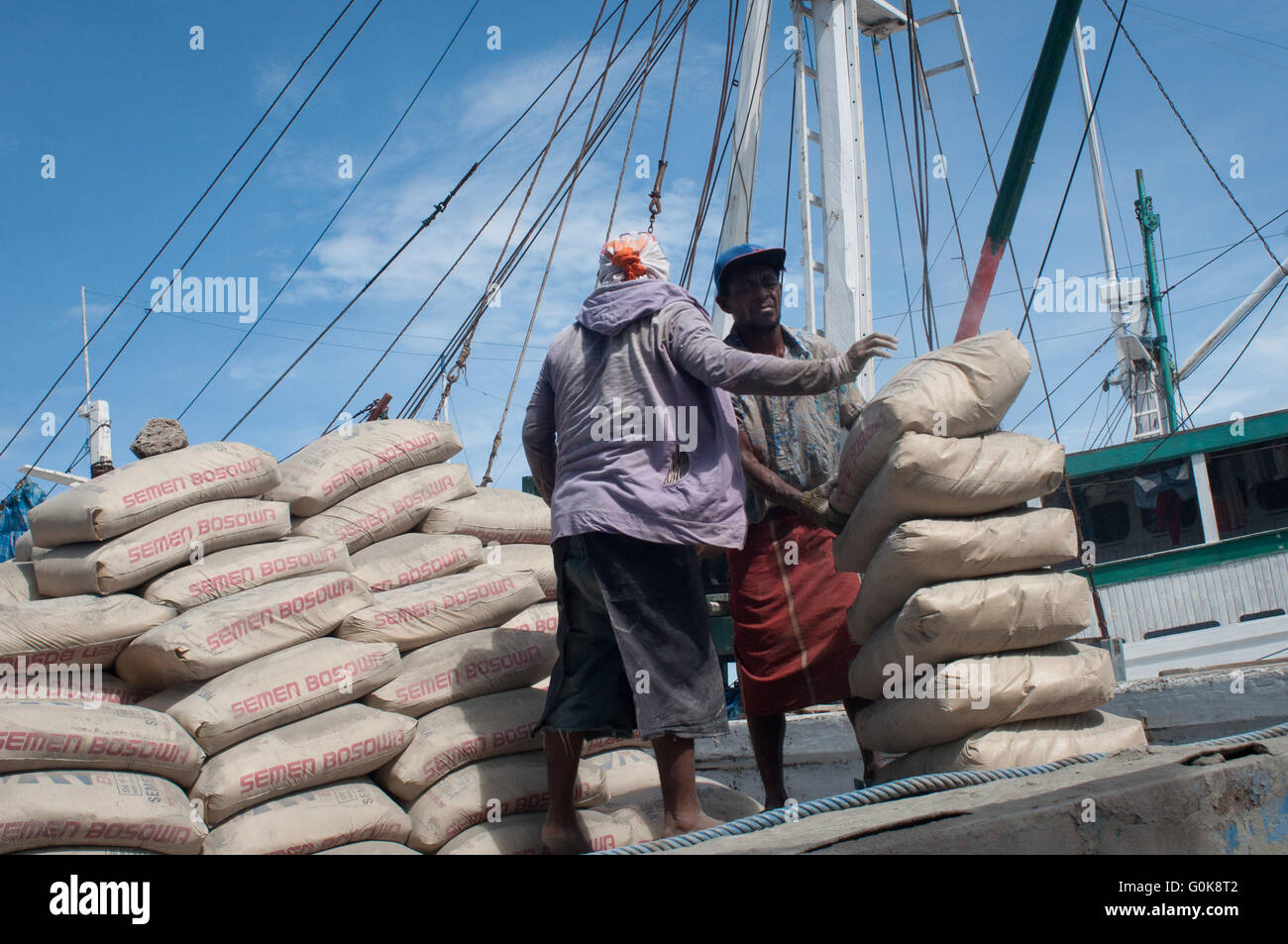 Les travailleurs chargés des sacs de ciment à la coque d'un bateau au port de Paotere à Makassar, Indonésie. Banque D'Images