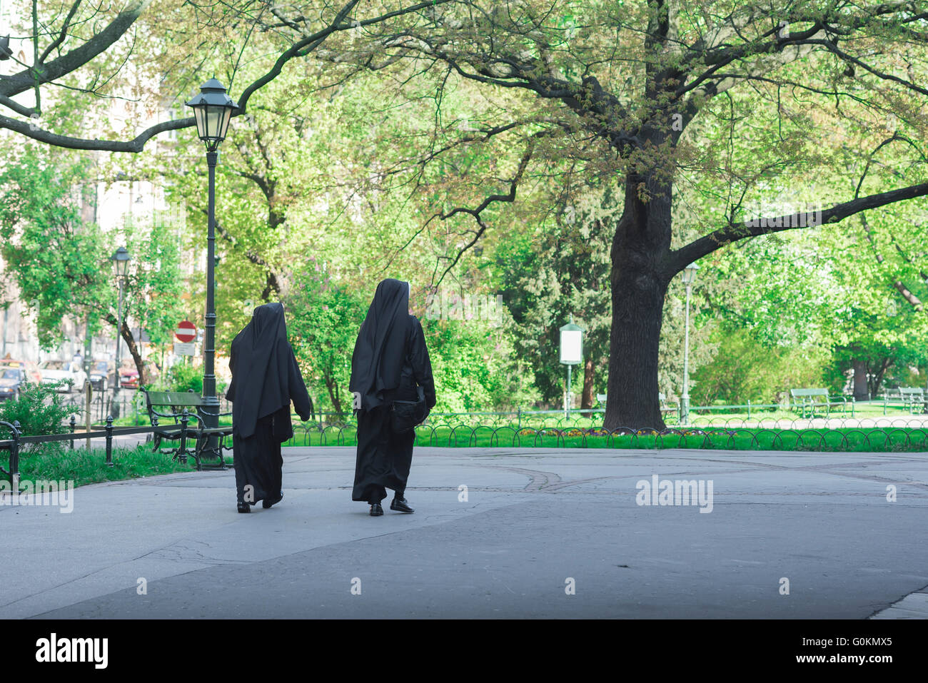 Marche des religieuses, vue arrière d'une paire de religieuses marchant à travers Planty Park dans le centre de Cracovie, Pologne. Banque D'Images