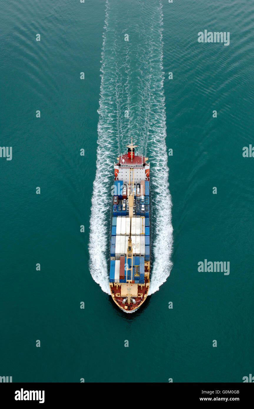 Porte-conteneurs le sud de Lily têtes hors de l'Auckland Harbour avec des conteneurs de transport et des voitures sur le pont. Banque D'Images