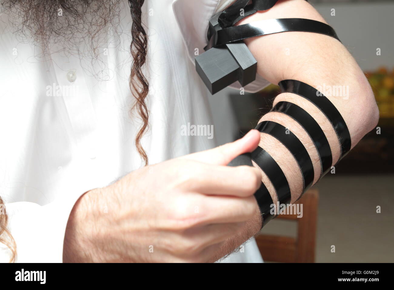 L'homme juif enveloppé de tefillin prier . Un religieux juif orthodoxe avec bras-tefillin sur sa main gauche prie Banque D'Images