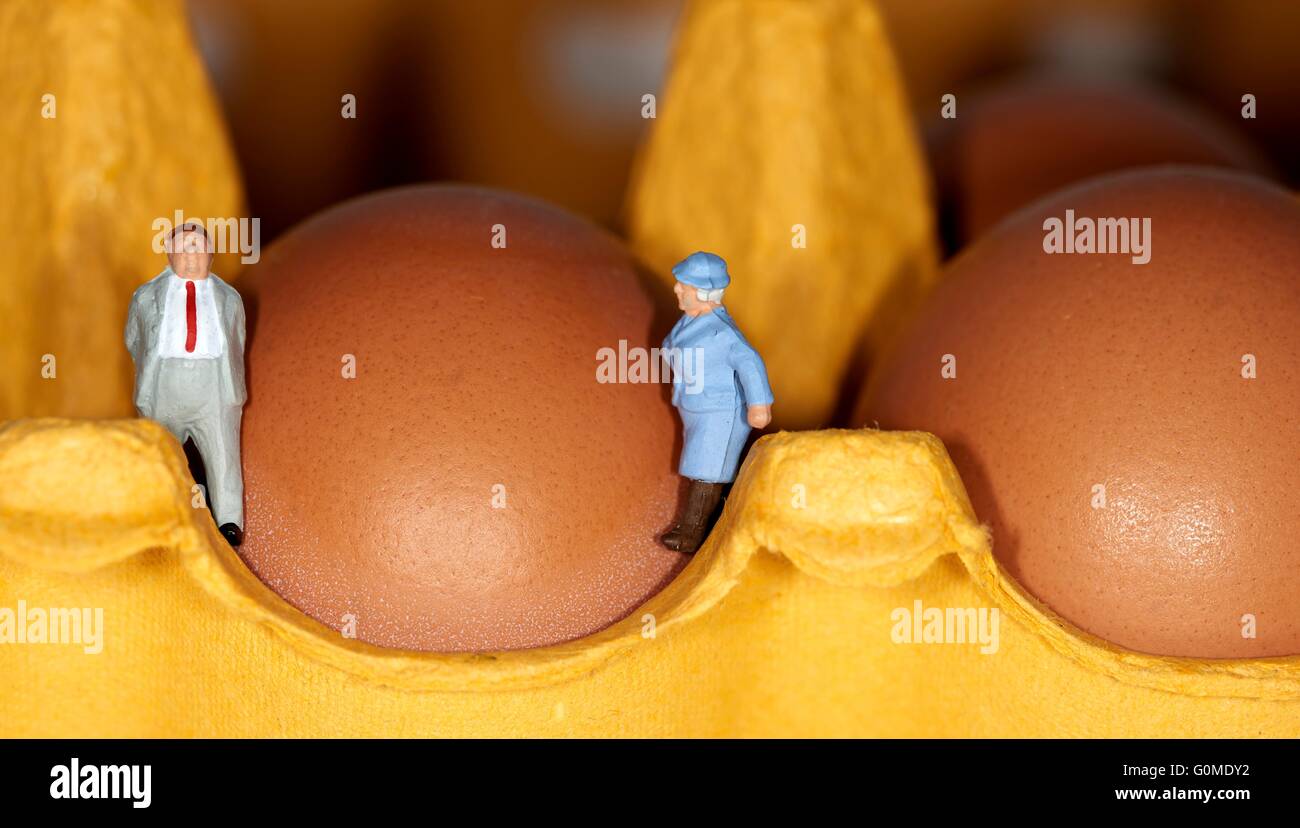Un couple retraité figurine miniature debout sur un oeuf boîte à côté de 2 oeufs Banque D'Images