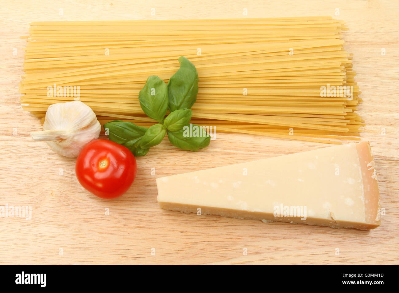 Spaghetti crus, l'ail, tomates, basilic et parmesan sur une planche à découper en bois Banque D'Images