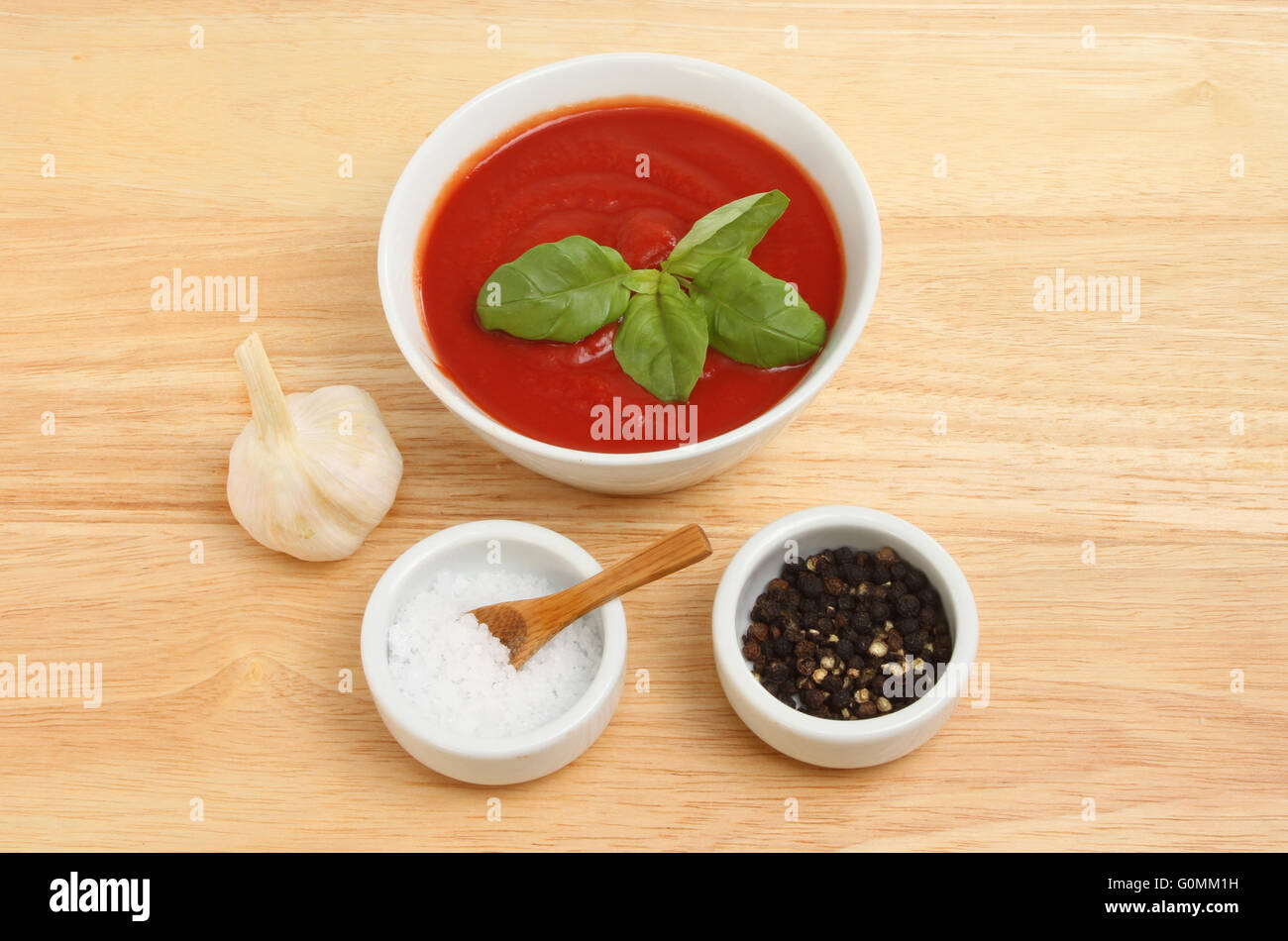 Utilisez du coulis de tomate dans un bol avec le basilic, l'ail et le sel et le poivre sur une planche à découper en bois Banque D'Images