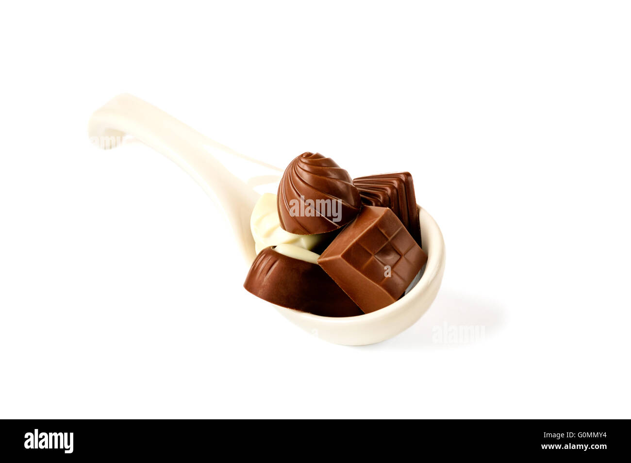 Cuillère en céramique plein de pralines en chocolat isolé sur blanc. Banque D'Images