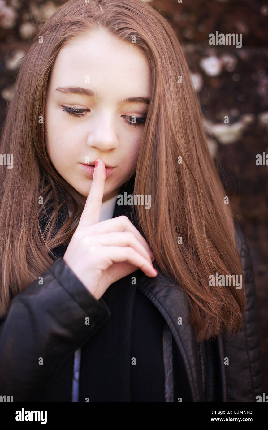 Adolescente avec son doigt sur ses lèvres pour garder le silence Banque D'Images