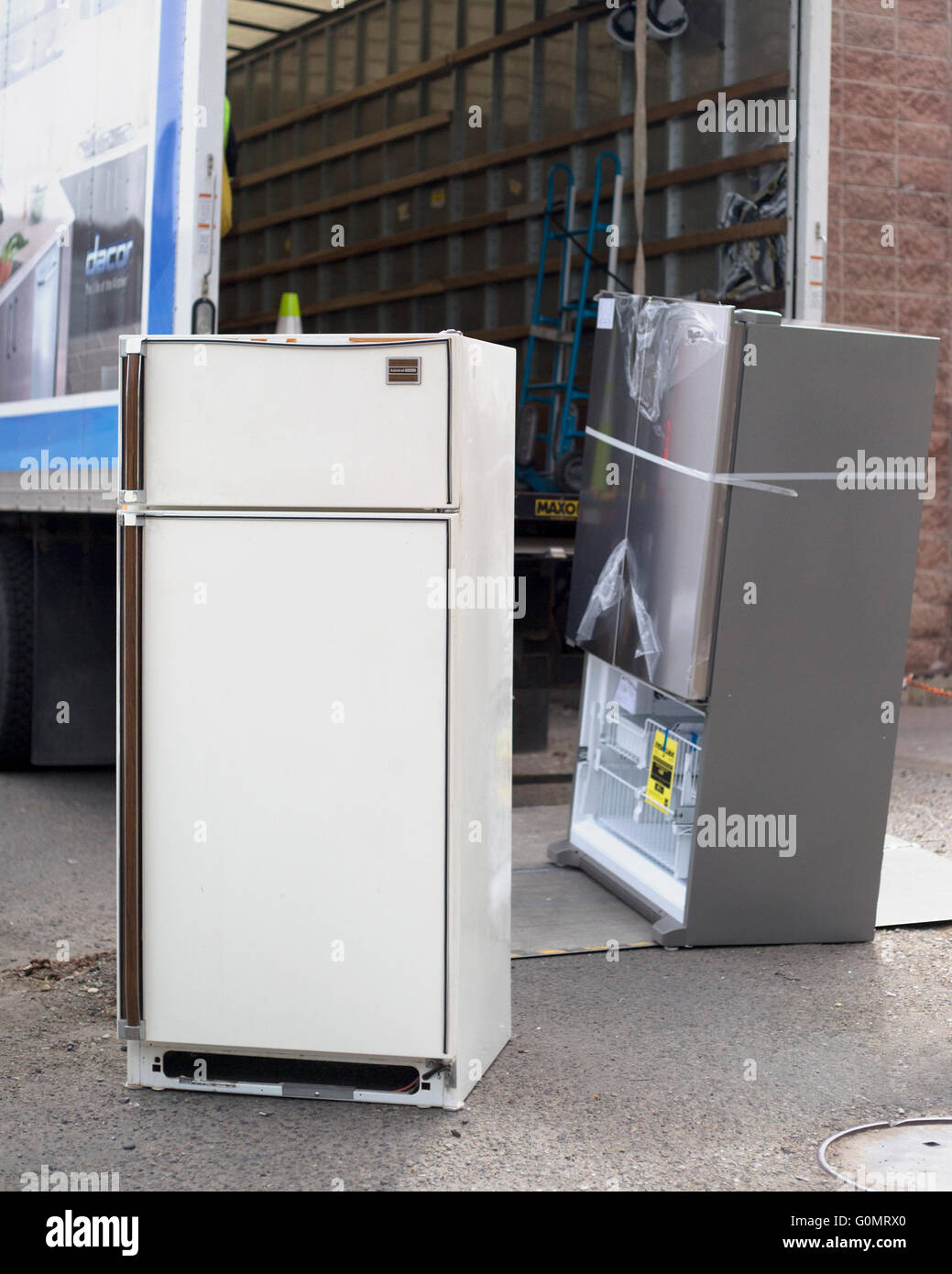 Un réfrigérateur obsolète vieux de plusieurs décennies (façade) est transporté pour être mis au rebut de manière appropriée et remplacé par un nouvel appareil plus économe en énergie (à l'arrière). Banque D'Images