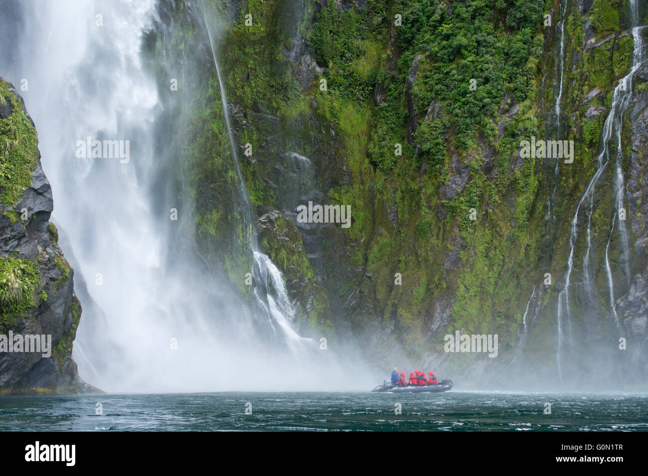 Nouvelle Zélande, île du Sud, le Parc National de Fiordland, Milford Sound. Les touristes explorant le fjord par zodiac. Banque D'Images