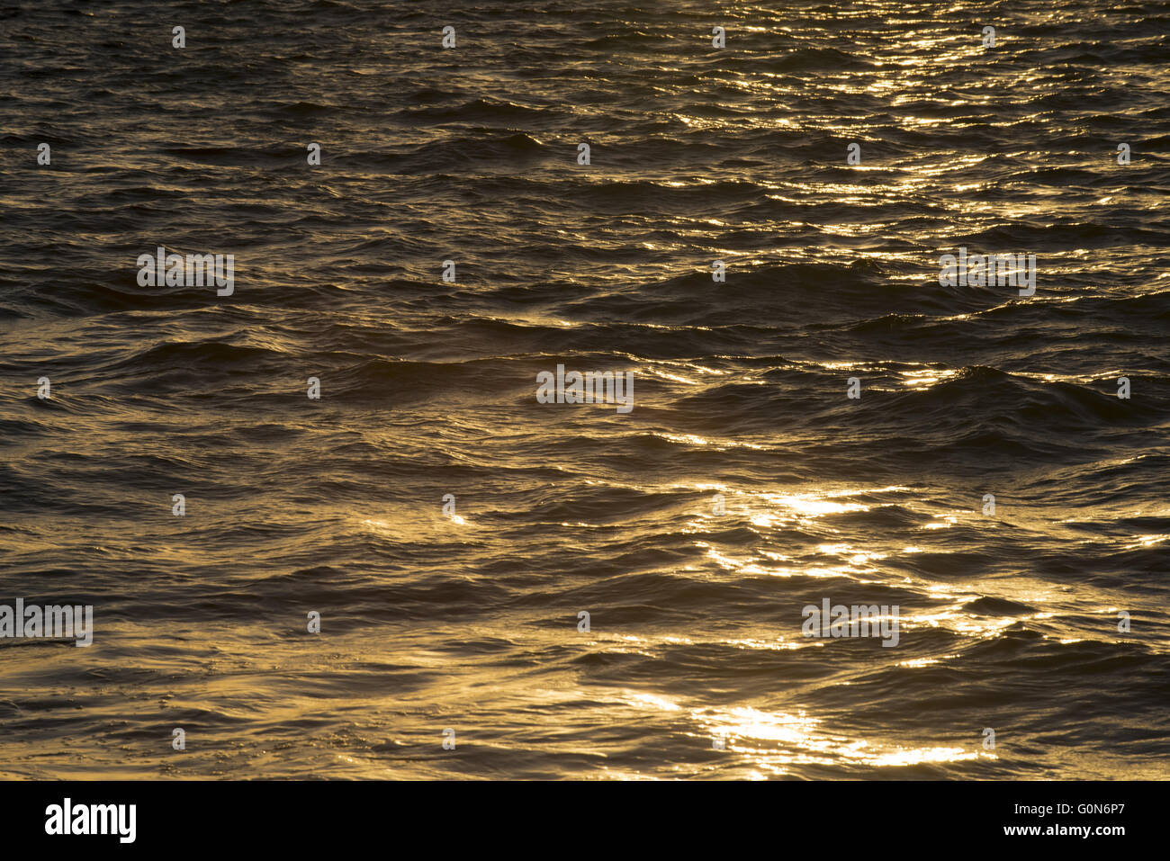 Les vagues de l'océan reflétant la lumière du soleil au coucher du soleil, l'eau de mer sur la surface tranquille. Banque D'Images