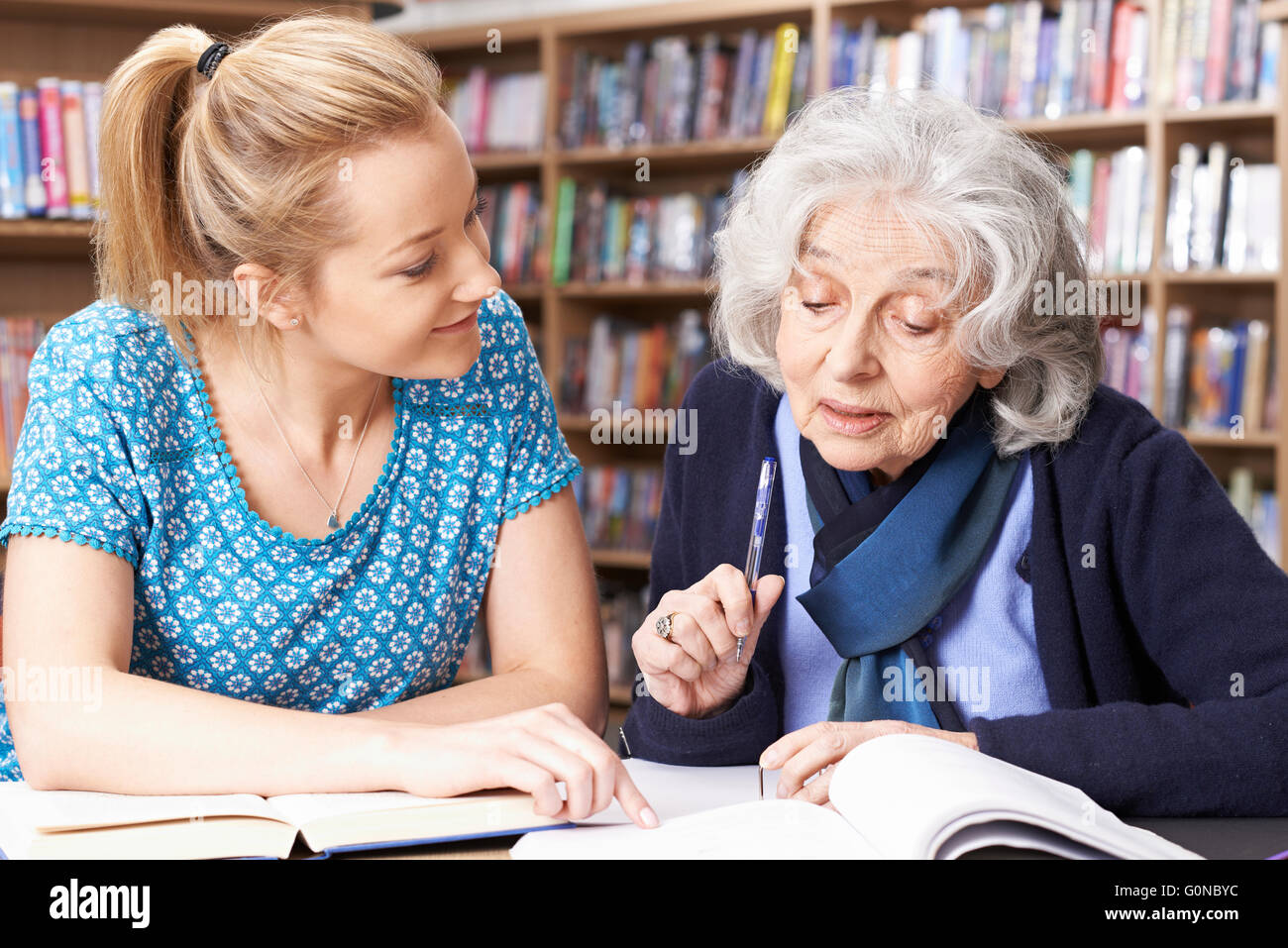 Hauts femme travaillant avec l'enseignant dans la bibliothèque Banque D'Images