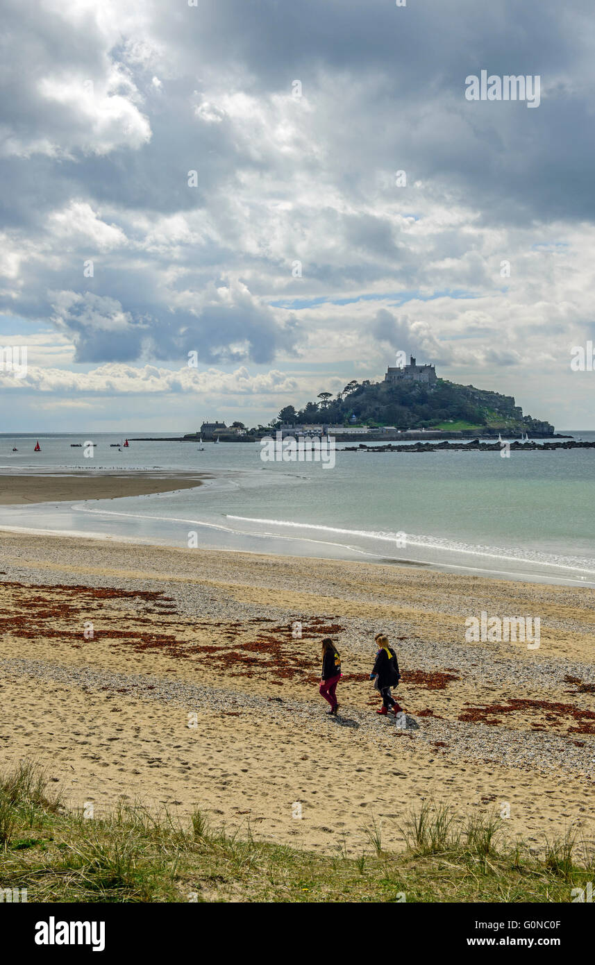 Plage de Marazion photographié dans le soleil avec trois dames la marche sur la plage et St Michael's Mount en arrière-plan Banque D'Images