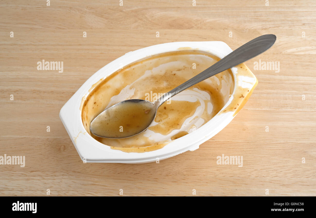 Un plat Repas dîner qui a été mangé avec une cuillère dans le bac en plastique sur une table en bois. Banque D'Images