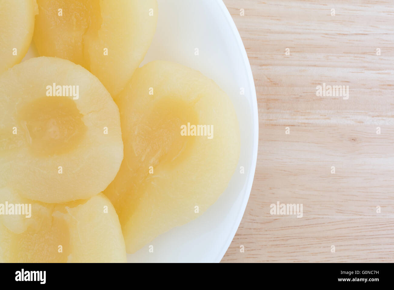 Haut fermer avis de plusieurs moitiés de poires sur une assiette blanche au sommet d'une table en bois. Banque D'Images