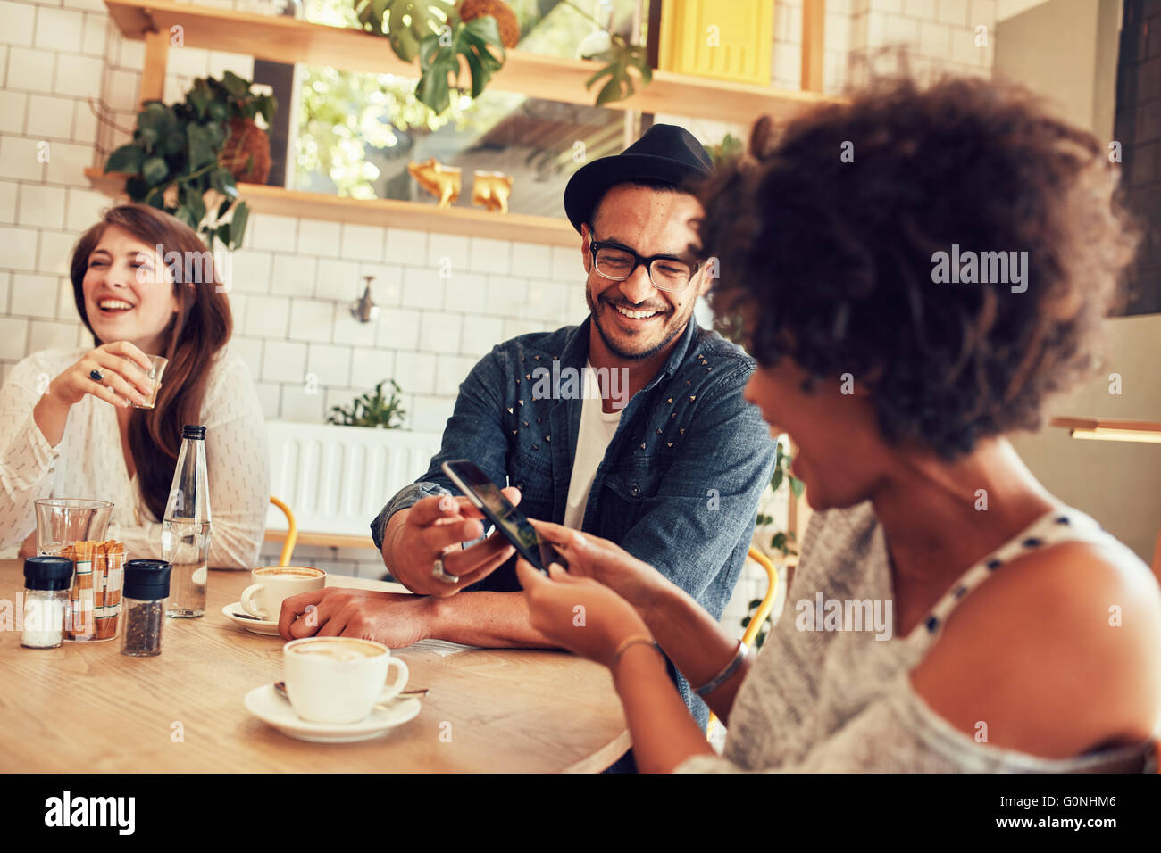 Portrait de jeunes amis parler dans le café et en regardant les photos sur téléphone intelligent. Heureux les jeunes gens ayant un grand temps à un Banque D'Images