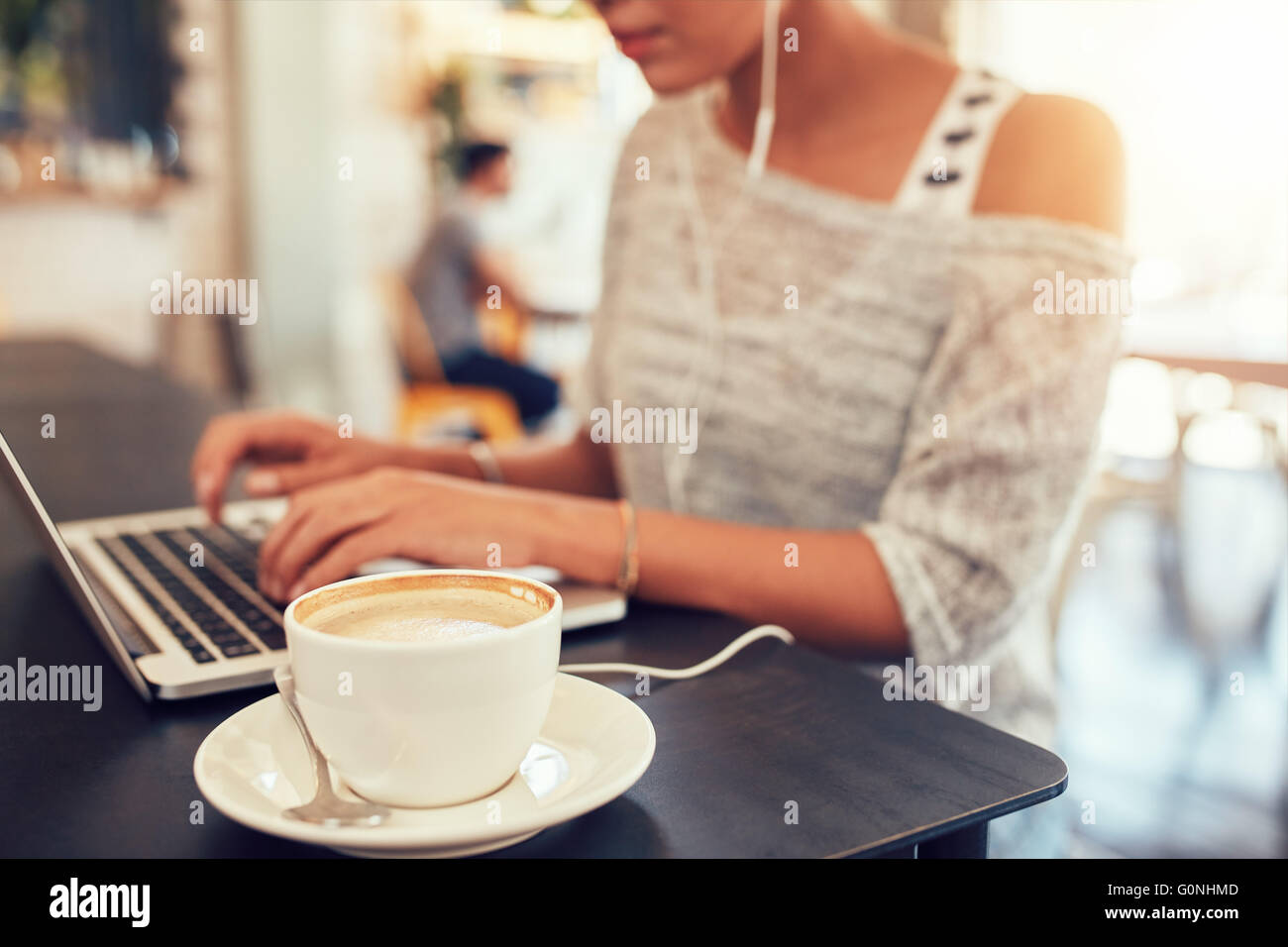Libre coup de tasse de café sur la table de café avec une femme travaillant sur un ordinateur portable. Banque D'Images