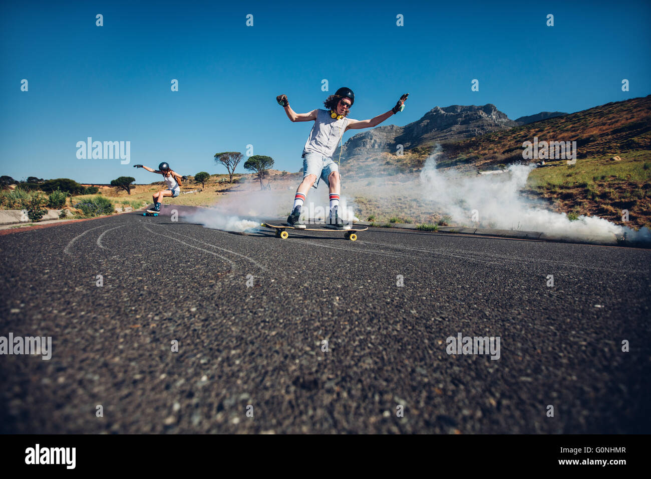 Tourné en plein air de jeunes gens patiner dans la rue. L'homme et la femme la pratique de patinage. Conseil long avec grenade fumigène. Banque D'Images