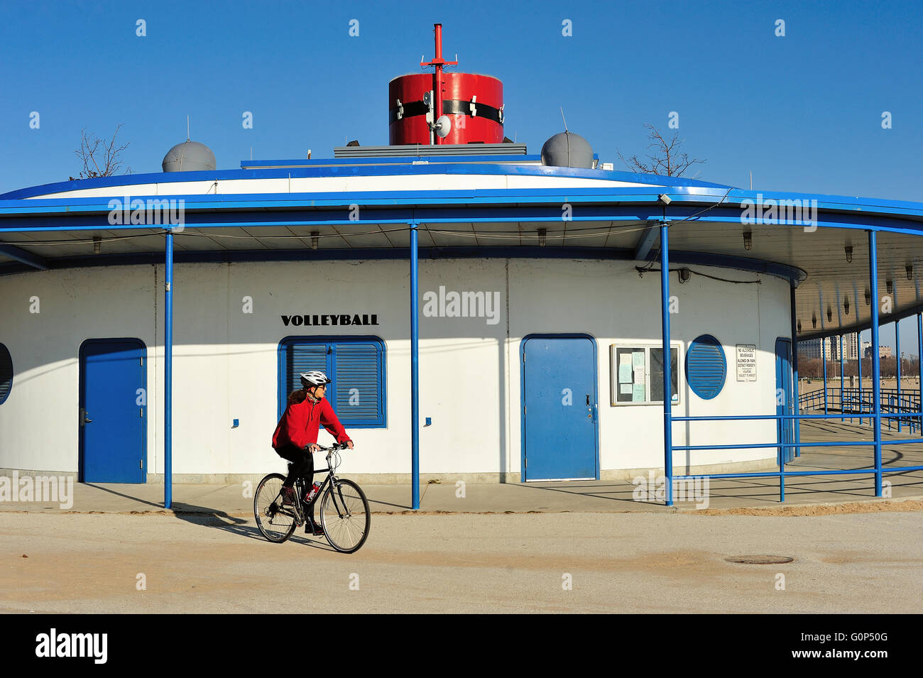 Un cycliste solitaire en passant par le monument en forme de bateau, d'un hangar à bateaux à Chicago's North Avenue Beach. Chicago, Illinois, USA. Banque D'Images