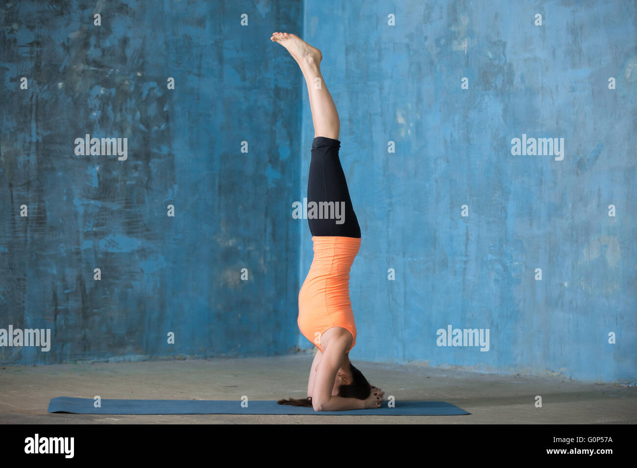 Belle jeune femme vêtue de vêtements de yoga à l'intérieur. Yogi girl working out in grunge mur bleu avec intérieur Banque D'Images