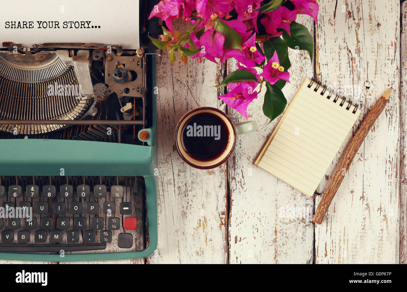 Image de machine à écrire vintage avec expression "partager votre histoire', ordinateur portable blanc, tasse de café sur la table en bois Banque D'Images