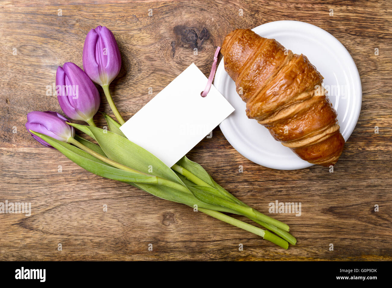 Croissant, tulipes et violettes sur la carte Vue de dessus de table en bois Banque D'Images