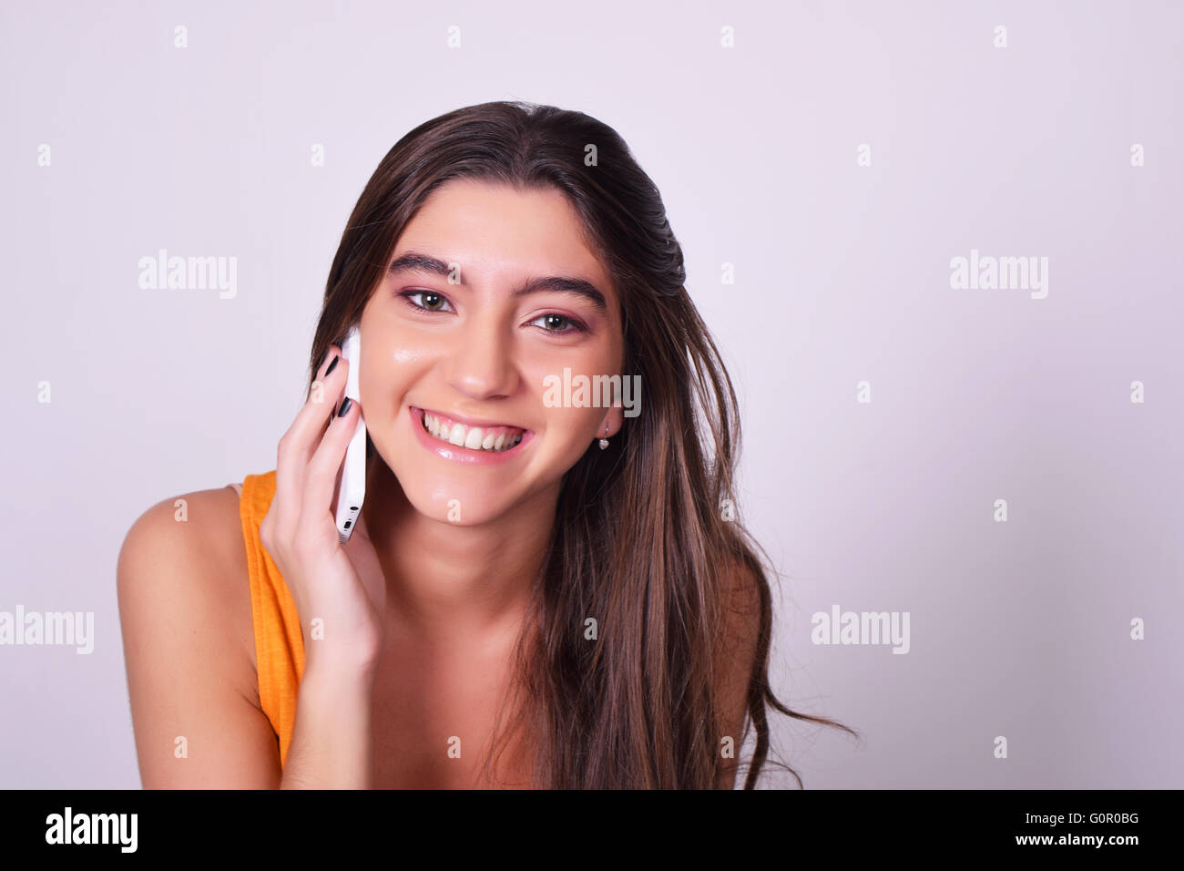 Portrait of Hispanic / jeune femme de race blanche à l'aide d'un téléphone mobile. Femme parlant au téléphone, isolés sur brackground gris. Banque D'Images