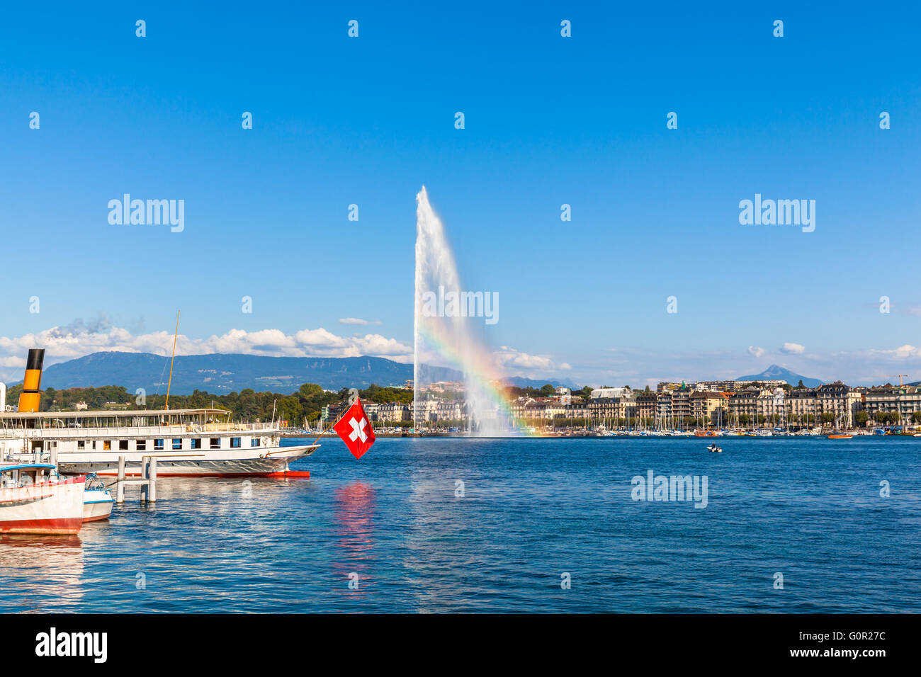 Belle vue sur le jet d'eau fontaine avec arc-en-ciel dans le lac de Genève et la ville de Genève, Suisse, au coucher du soleil Banque D'Images