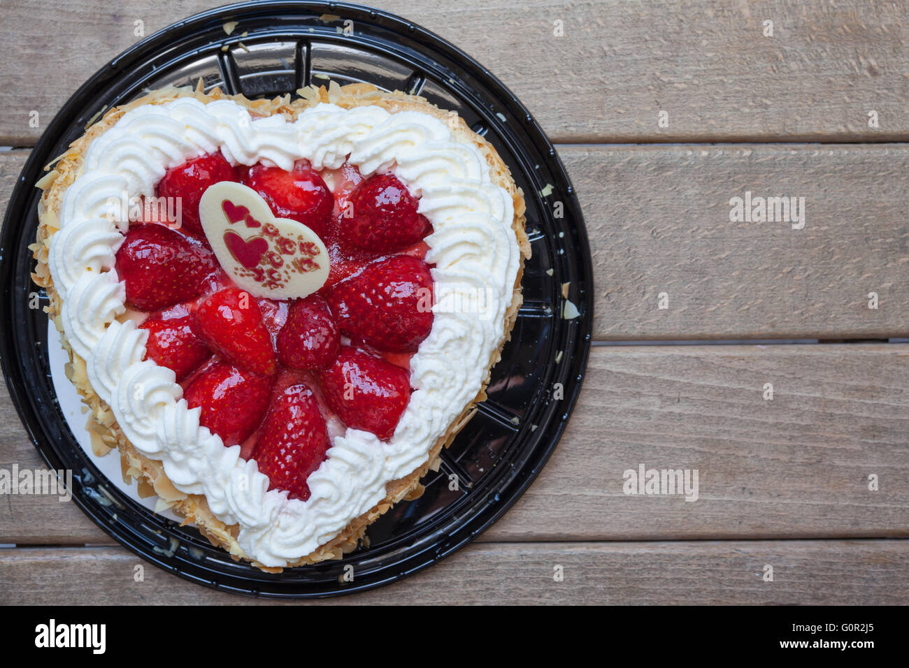 Gâteau en forme de coeur avec fraise et d'amande, cadeau pour la Saint-Valentin. Avec fond de bois, copie de l'espace disponible. Banque D'Images