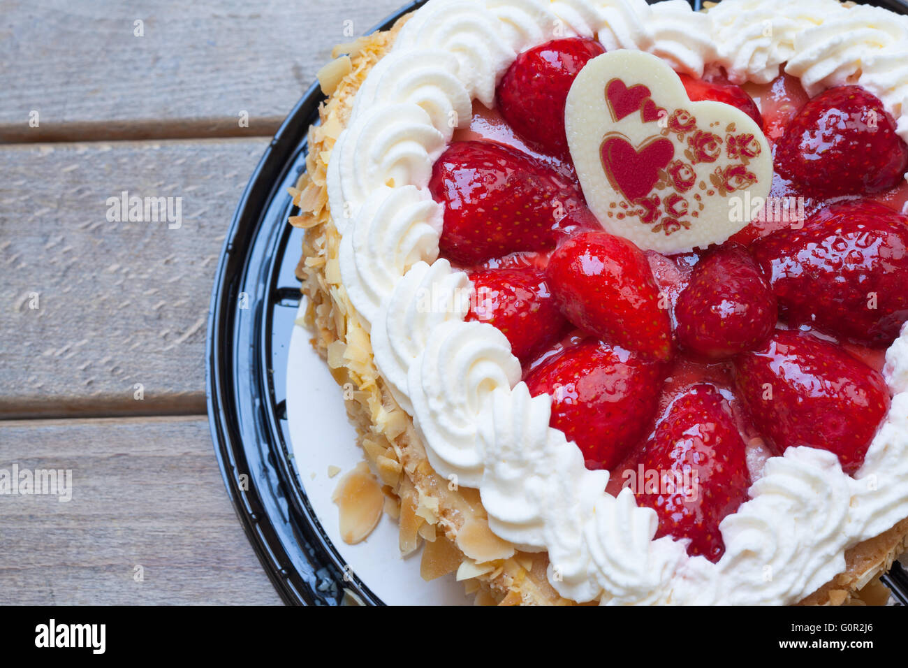 Gâteau en forme de coeur avec fraise et d'amande, cadeau pour la Saint-Valentin. Avec fond de bois, copie de l'espace disponible. Banque D'Images
