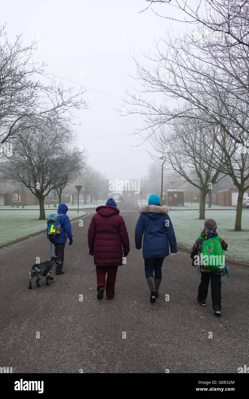 Enfants à l'école à pied avec la mère, la grand-mère et le chien Banque D'Images