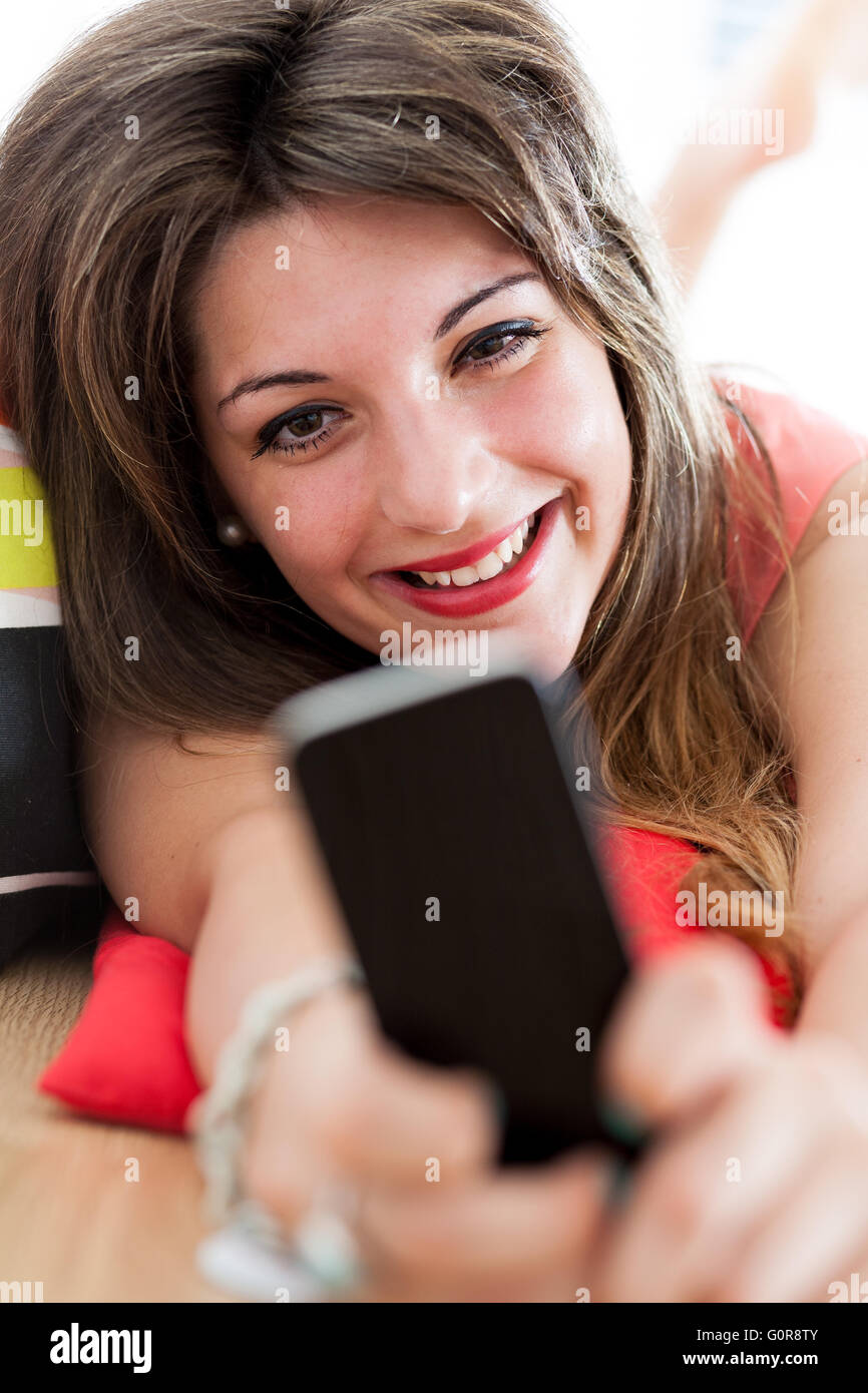 Smiling woman regarder quelque chose dans son Smartphone à la maison Banque D'Images