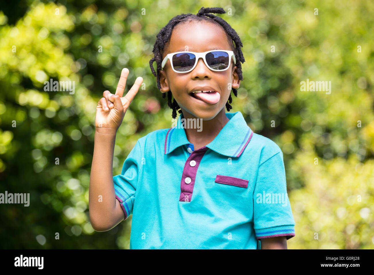 Garçon tendre la langue portant des lunettes de soleil Banque D'Images