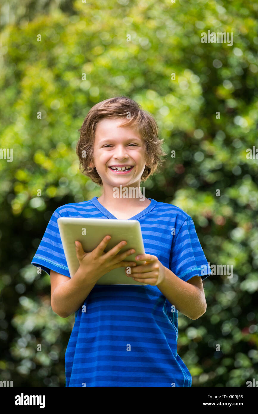 Un petit garçon qui sourit avec un ordinateur tablette Banque D'Images