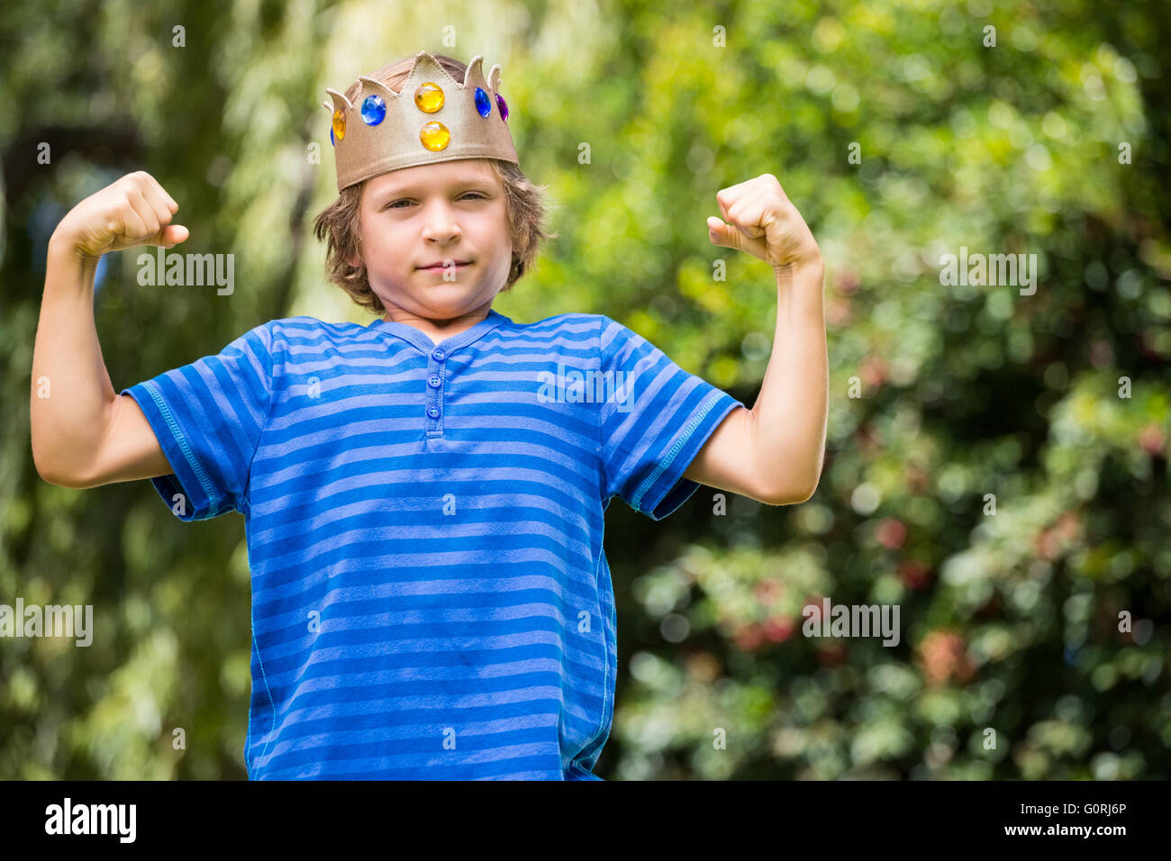 Cute boy avec une couronne montrant ses muscles Banque D'Images