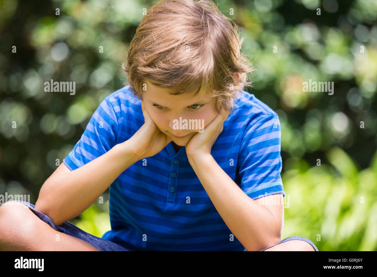 Portrait of cute boy sitting et bouder Banque D'Images