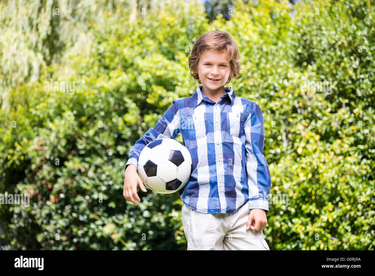 Portrait of cute boy smiling and holding a soccer ball Banque D'Images