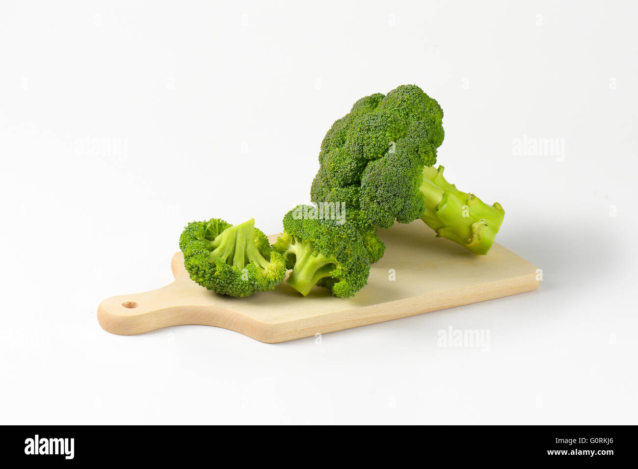 Tête de brocoli frais et des morceaux sur une planche à découper Banque D'Images