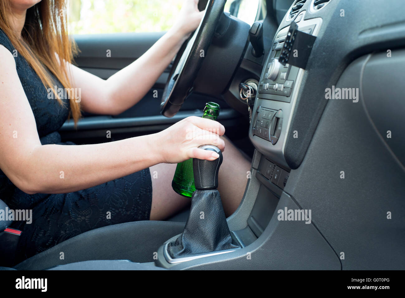 Photo de femme à boire de l'alcool dans la voiture. Banque D'Images