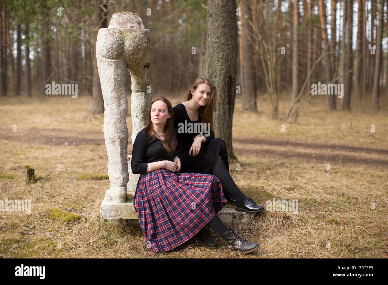 Teen girls sitting on the broken sculpture dans le parc. Banque D'Images