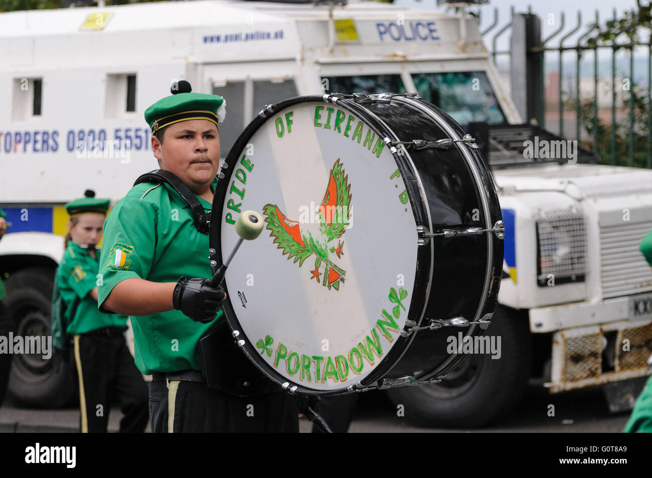 Un membre d'une bande de flûte républicaine irlandaise joue un tambour de basse en passant une Landrover PSNI. Banque D'Images