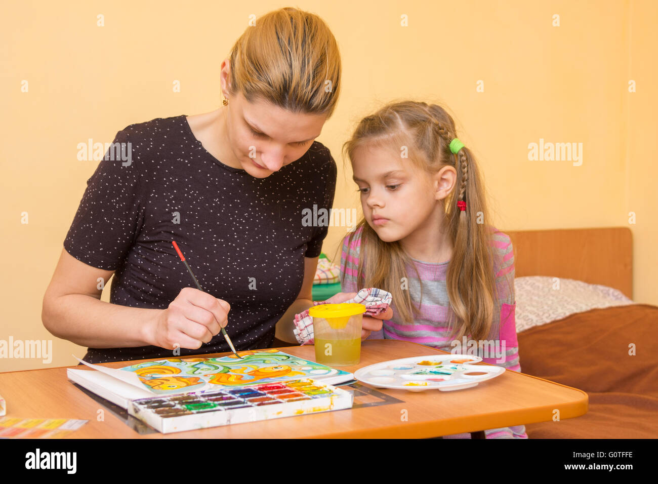 Artiste fille enseigne une petite fille à la table comme un tirage sur papier aquarelle Banque D'Images