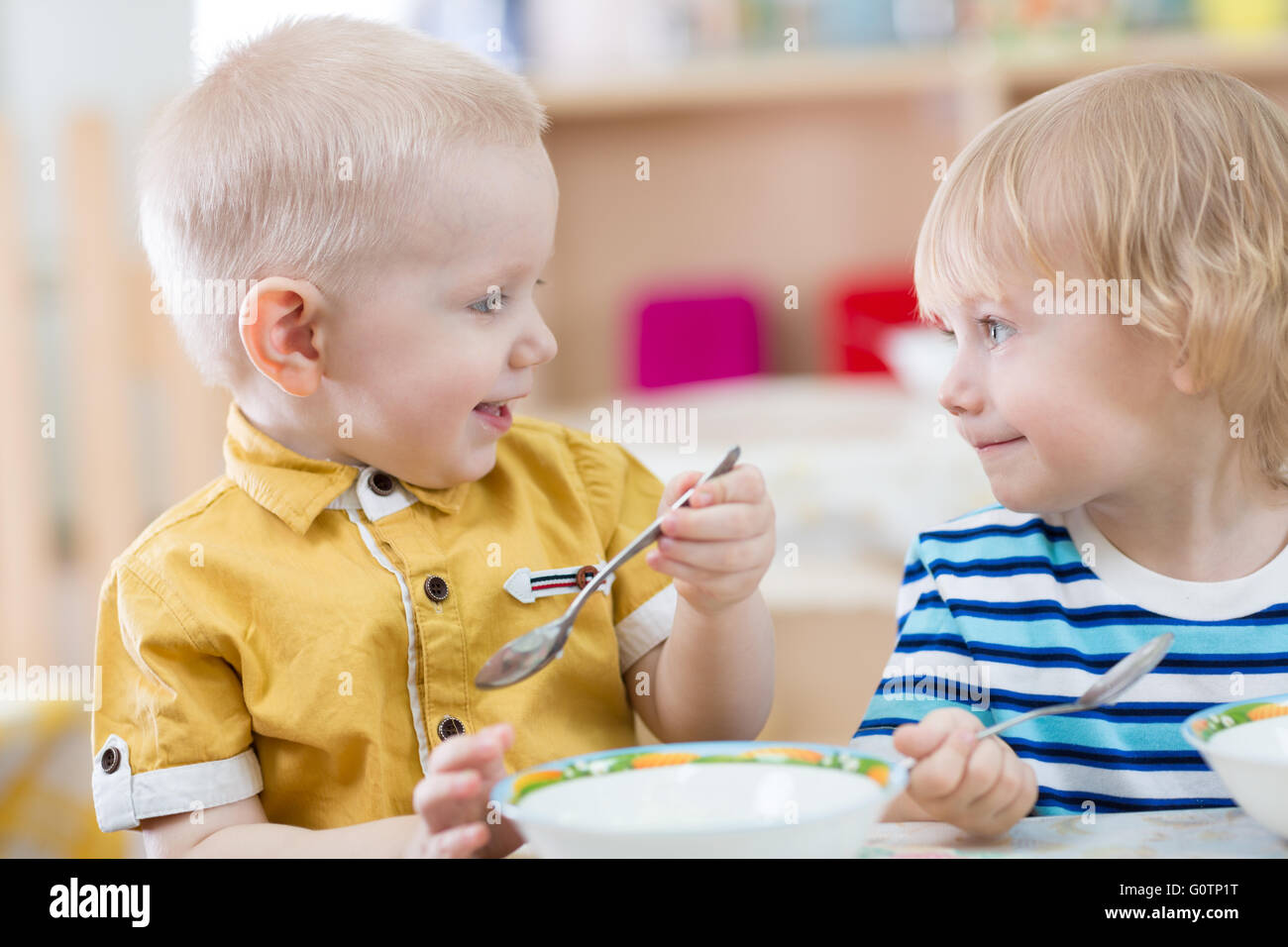 Deux drôles smiling très positif pour les enfants de manger dans le jardin d'enfants Banque D'Images