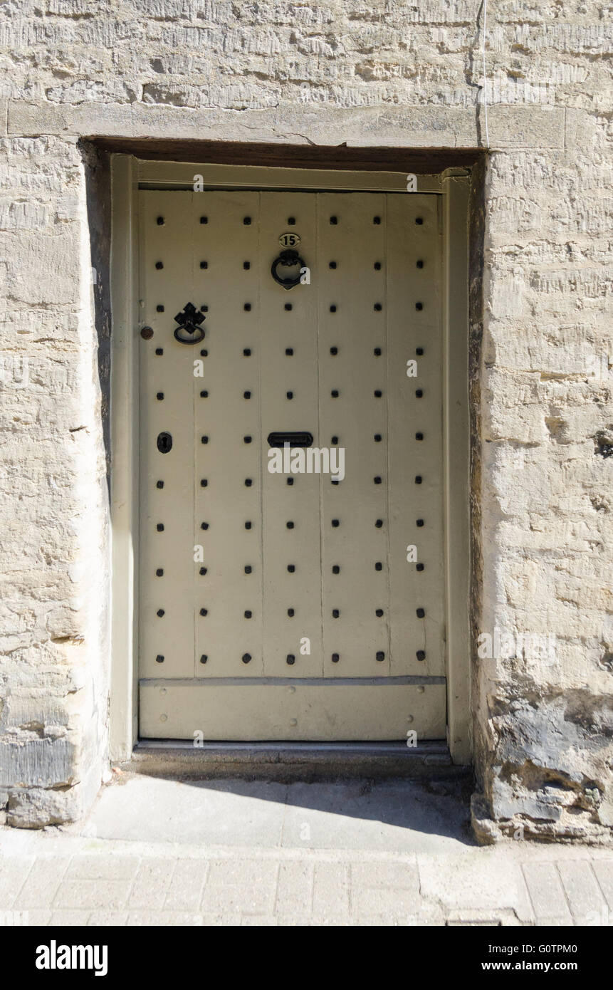 Vieille porte en bois clouté sur une maison en pierre de Cotswold à Cirencester Banque D'Images